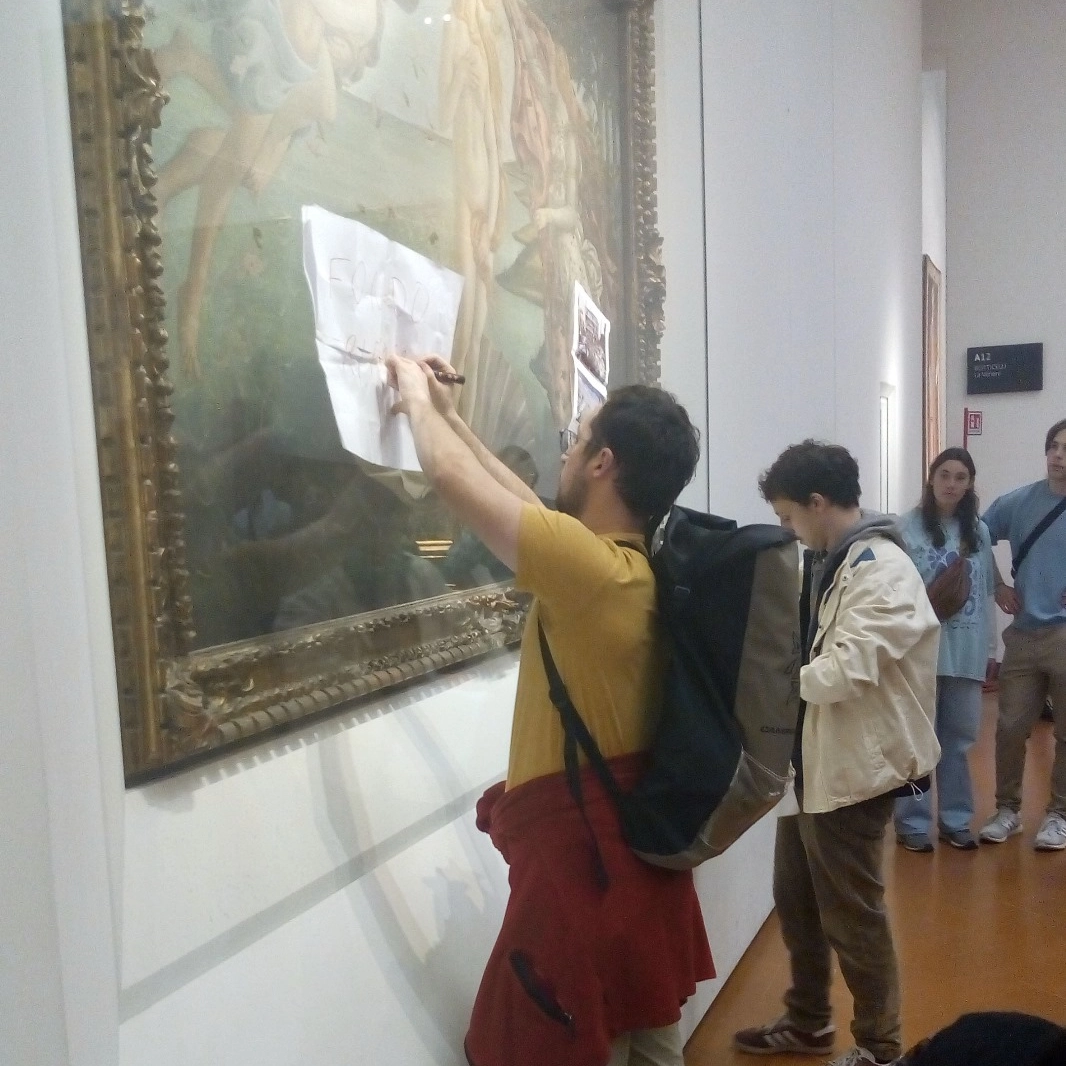 Gli ambientalisti mentre attaccano foto e manifesti al vetro della Venere di Botticelli