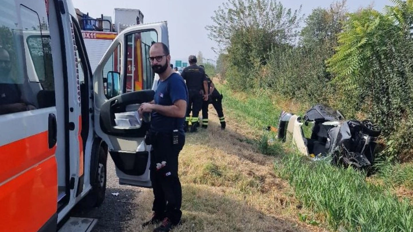 Un soccorritore e i vigili del fuoco; a destra, le lamiere dell’auto dopo lo schianto