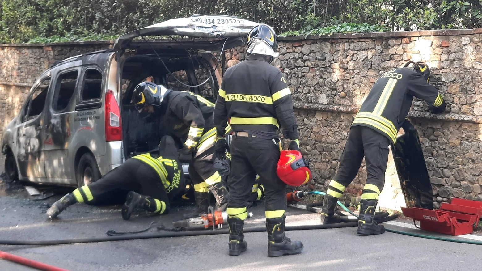 I vigili del fuoco intorno all'auto andata a fuoco