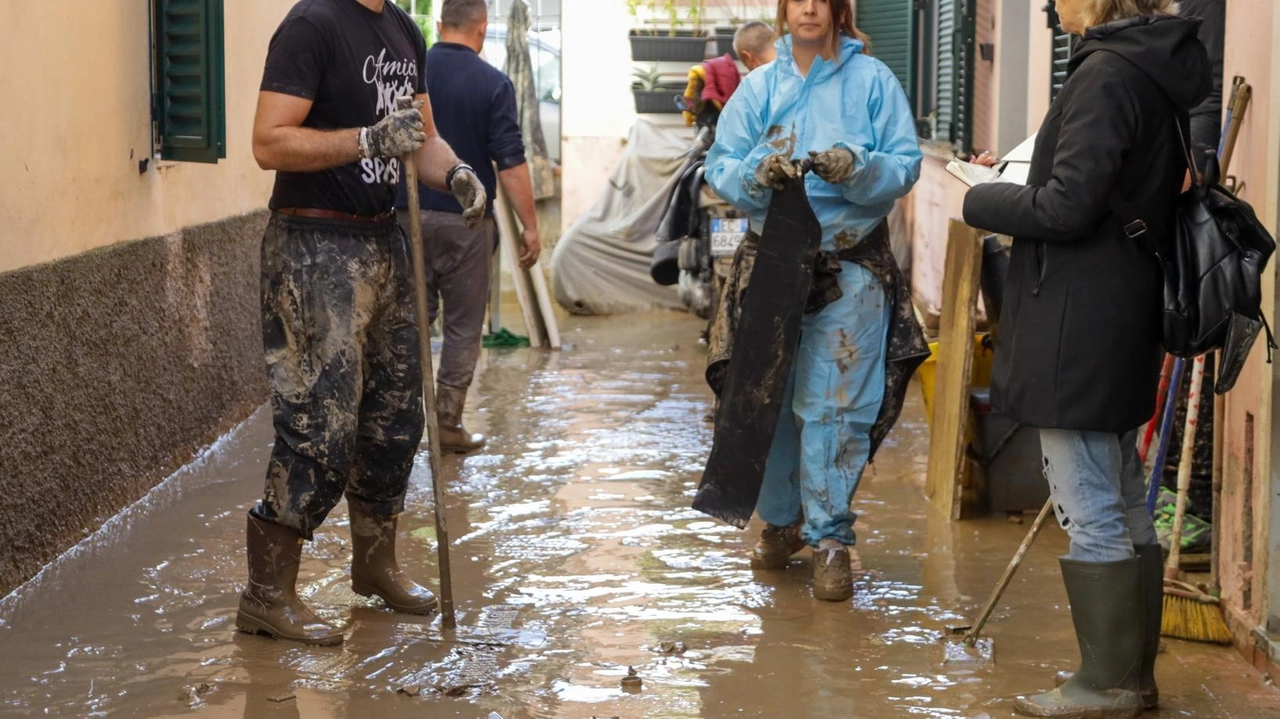 Volontari che puliscono una strada invasa da acqua e fango con l’alluvione di novembre (foto d’archivio Germogli)