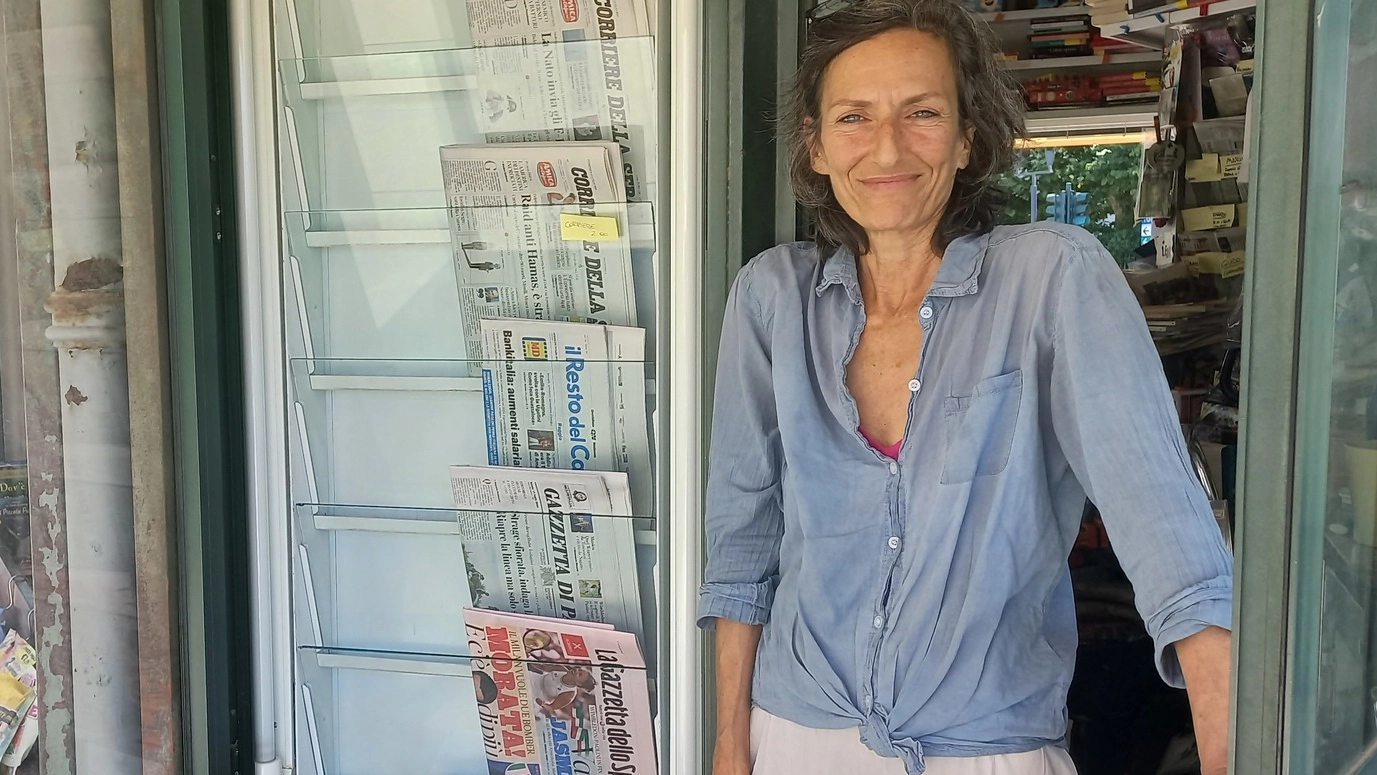 Mila Malavasi con i giornali e la cassetta esposti sul retro del chioscoion