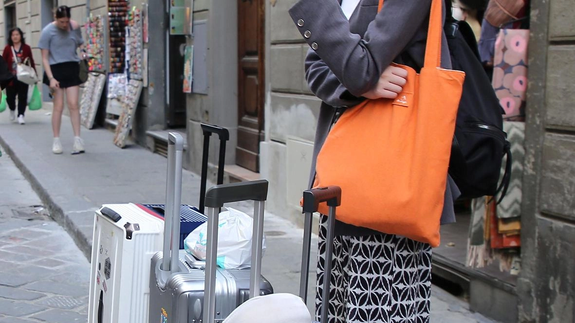 Una giovane turista in centro con l’immancabile trolley. In molti palazzi i fiorentini residenti sono ormai mosche bianche