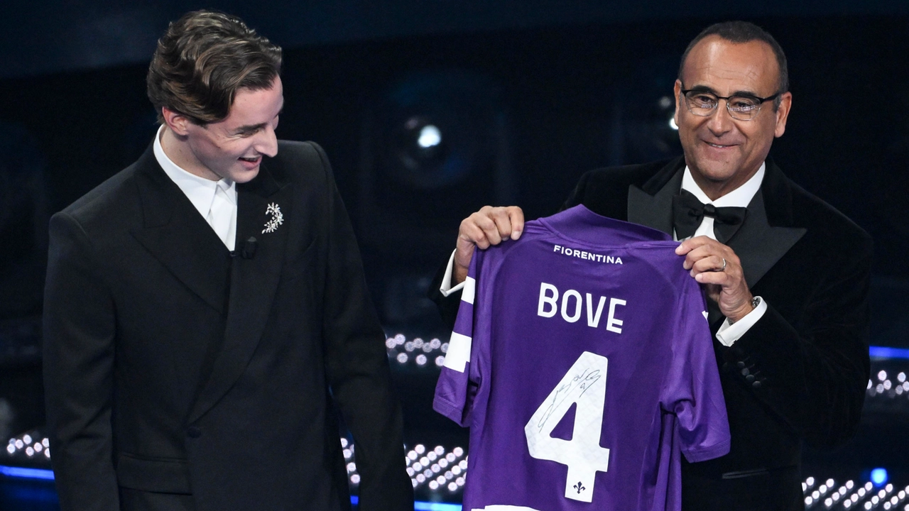 Edoardo Bove sul palco dell'Ariston regala la sua maglia della Fiorentina a Carlo Conti (Foto Ansa)