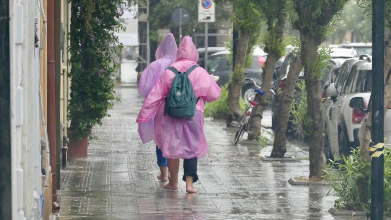 Persone in strada sotto il nubifragio (Foto Umicini)