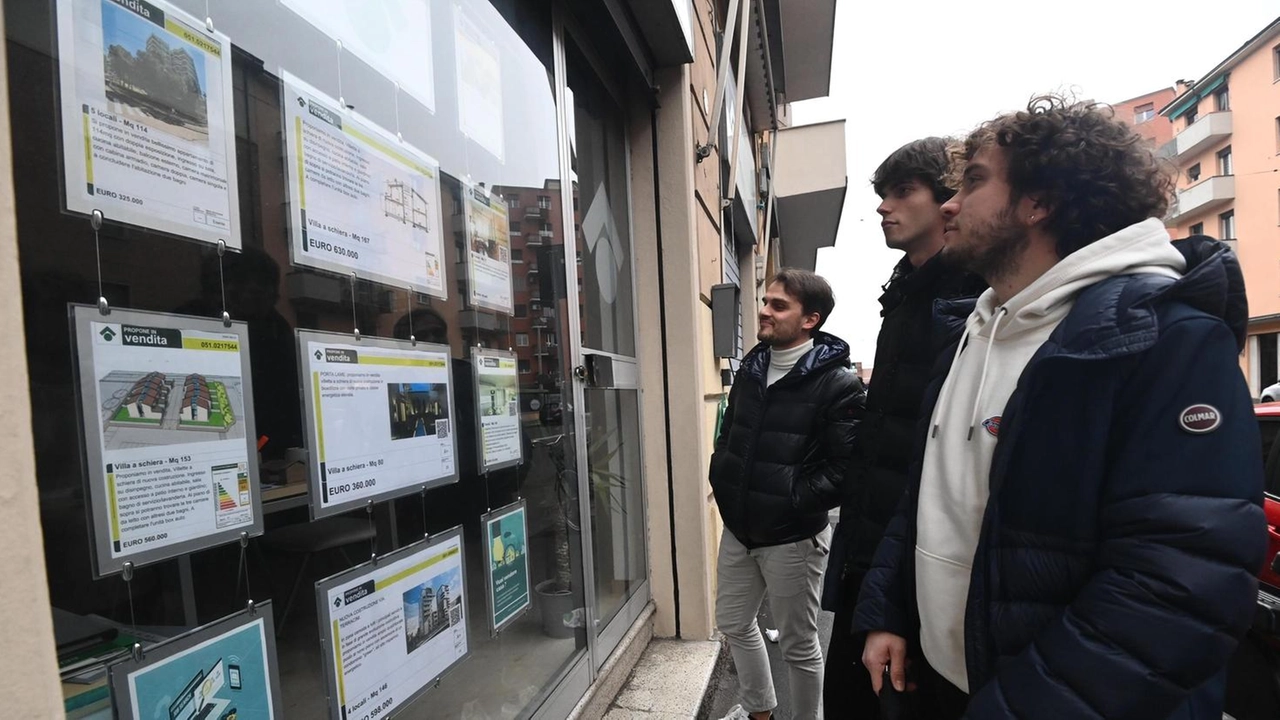 Giovani guardano la bacheca di un’agenzia per cercare una casa in affitto