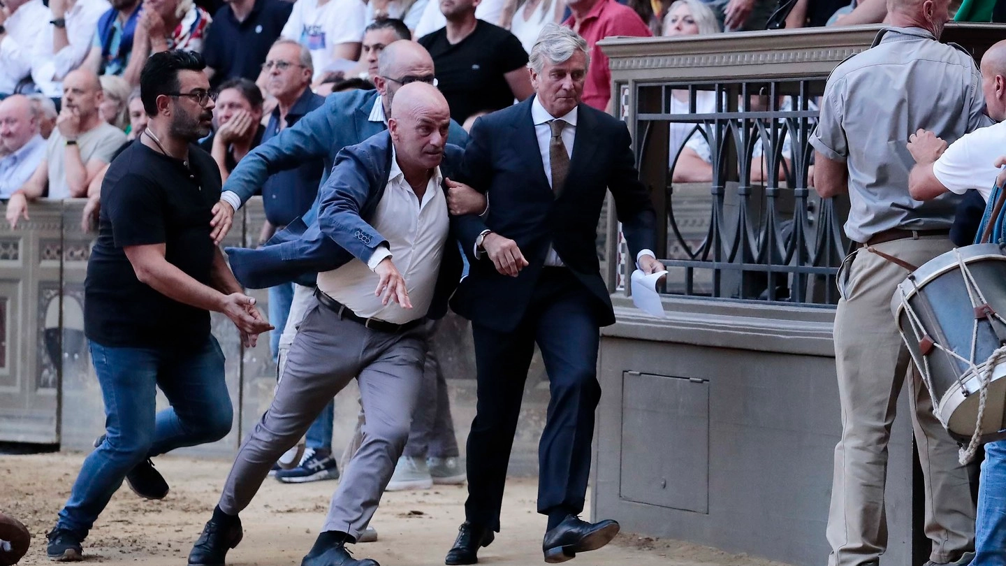 Il mossiere Bartolo Ambrosione esce da piazza del Campo scortato dalle forze dell’ordine dopo la mossa contestata (Foto Lazzeroni)