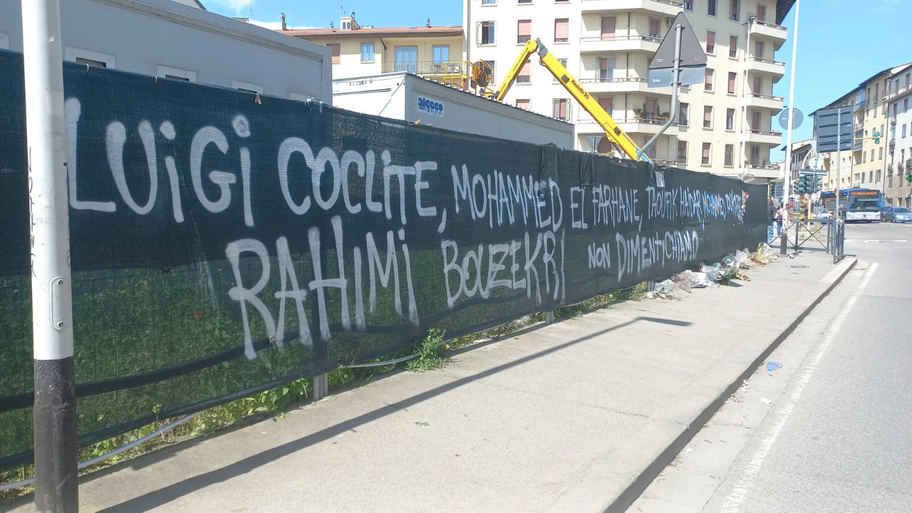 I nomi delle vittime scritti sul telo che copre il cantiere: "Non dimentichiamo"