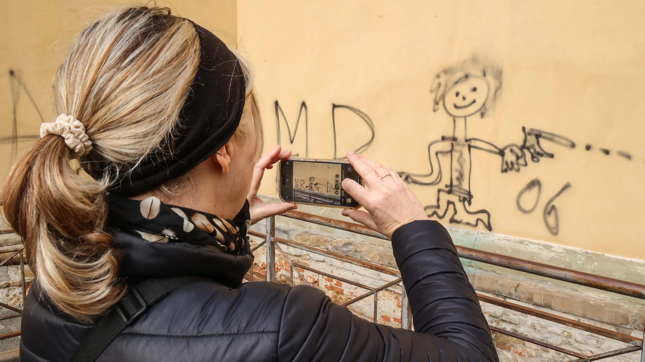 Una passante fotografa le scritte e i disegni che hanno imbrattato la basilica (foto Giuseppe Cabras/New Press Photo)